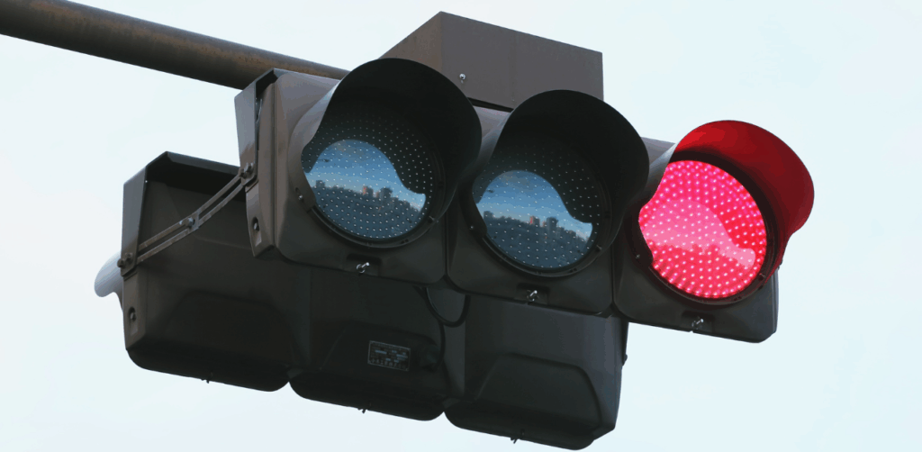 Close-up of a traffic light showing a bright red signal against the sky