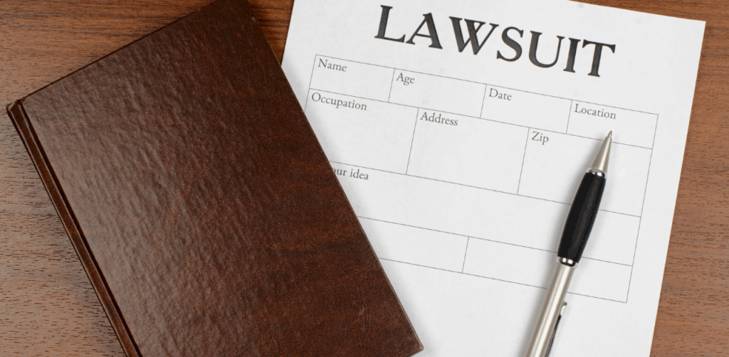 Lawsuit form with a pen and legal notebook on a wooden desk