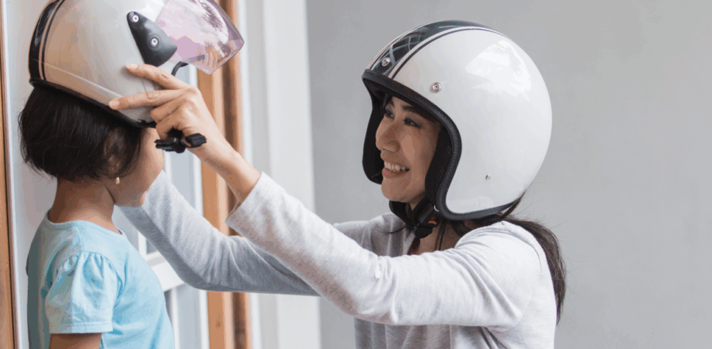 Mother helps daughter put on a motorcycle helmet