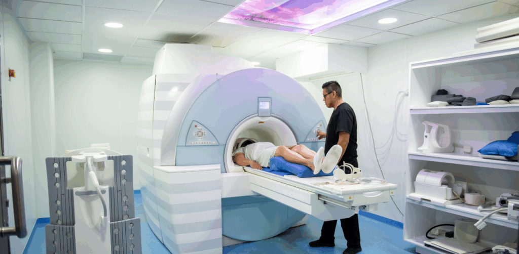 Patient undergoing MRI scan with technician standing nearby in hospital room