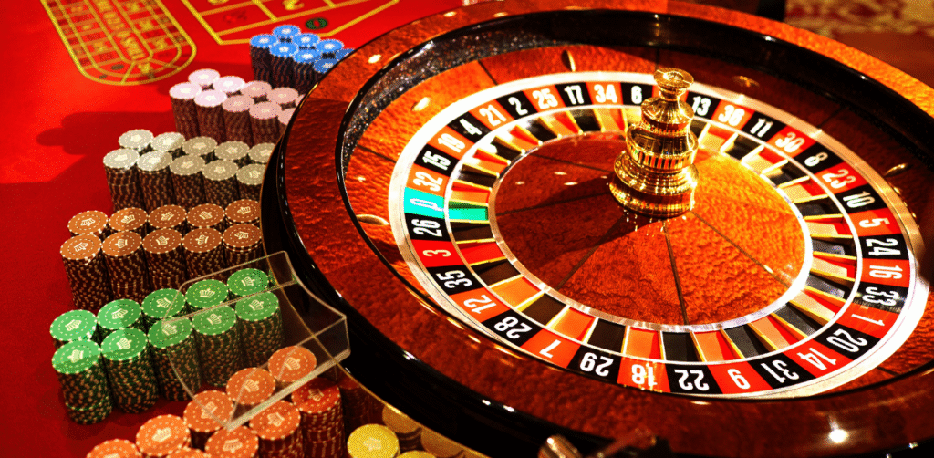 Close-up of roulette wheel and colorful casino chips on red table, symbolizing gambling, betting, and risk