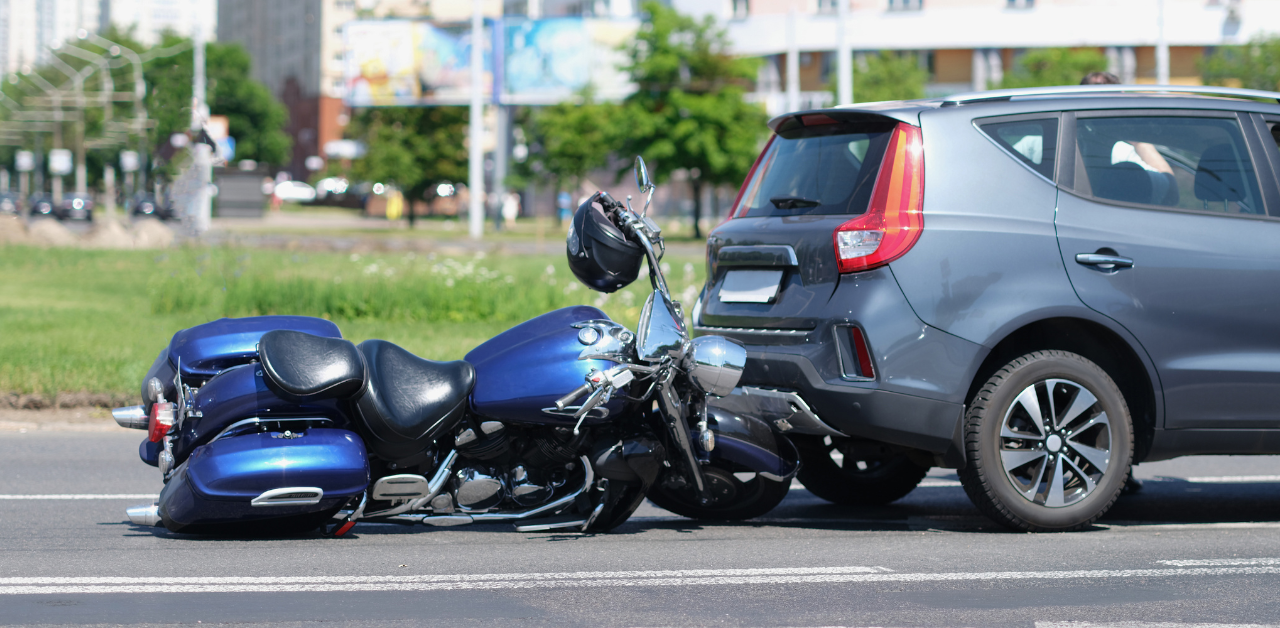 Motorcycle accident scene showing a bike crashed into the rear of a car
