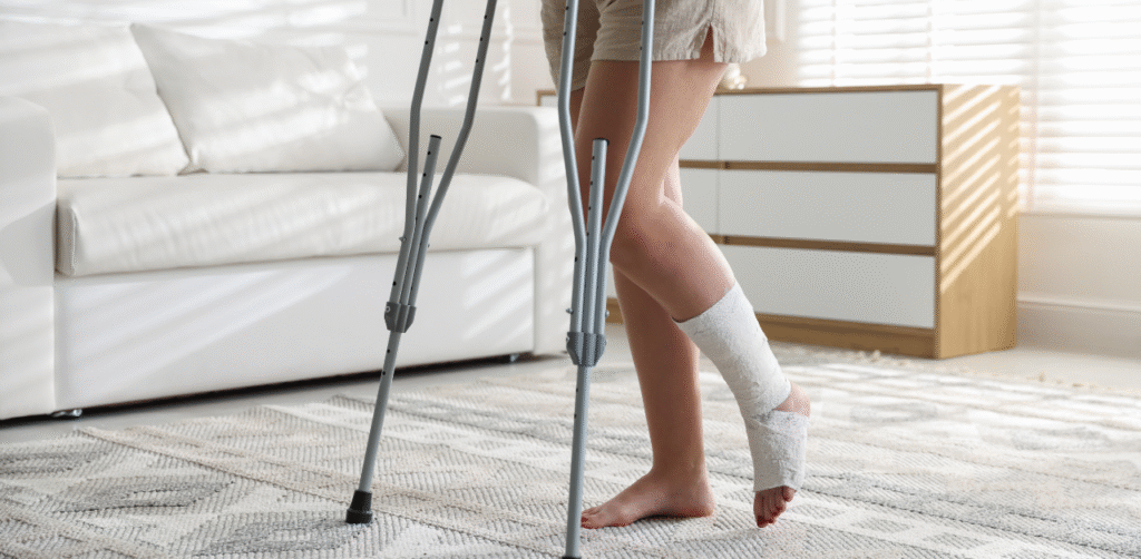 Person using crutches at home with a bandaged ankle, recovering from a leg injury