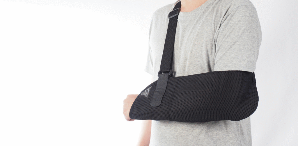 Person wearing a black arm sling, recovering from an injury with support gear