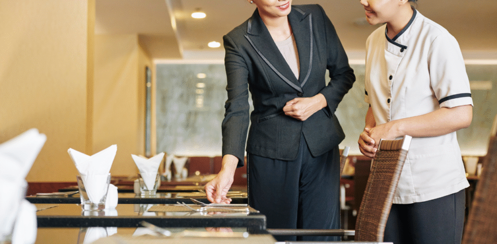 Restaurant staff training as manager shows server proper table setup, highlighting hospitality service and teamwork