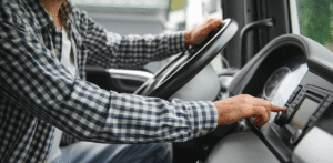 Truck driver adjusting dashboard controls while driving, highlighting focus and vehicle operation
