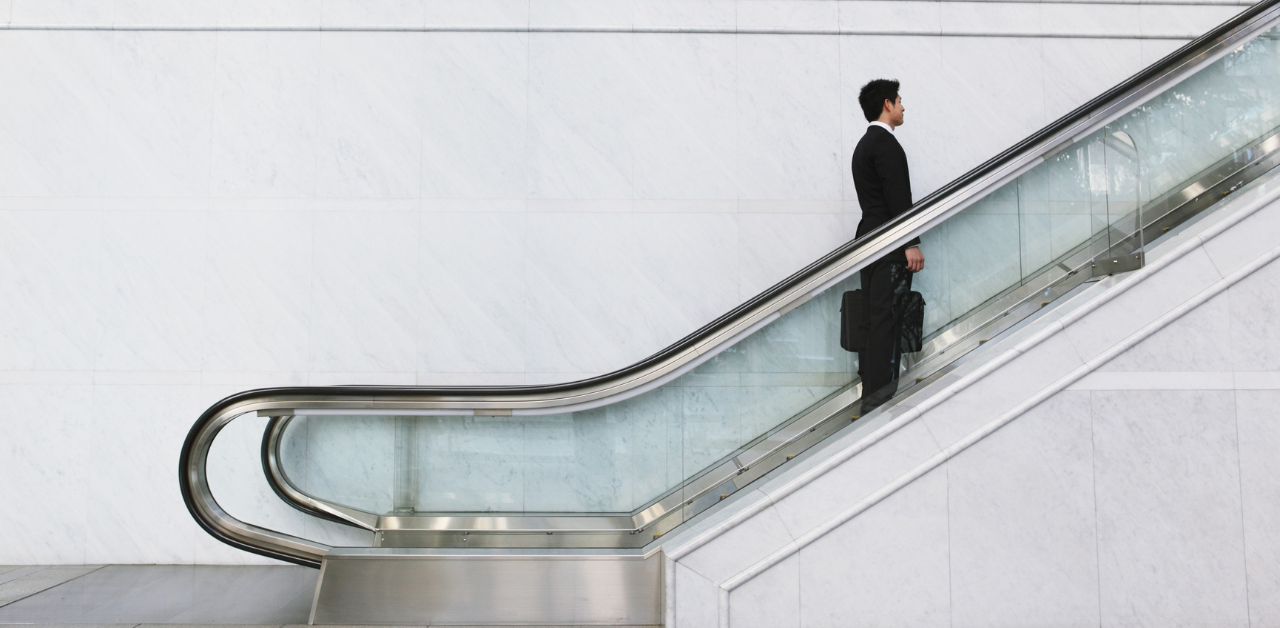 Businessman riding escalator in office, symbolizing Casino Escalator Accident Claims and workplace injury risks
