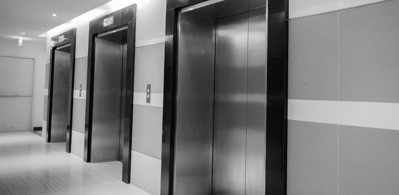 Clean modern hallway with multiple stainless steel elevator doors in a minimalist commercial building interior