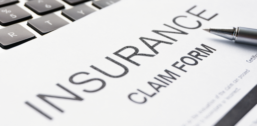 Close-up of an insurance claim form beside a pen and laptop keyboard on a desk