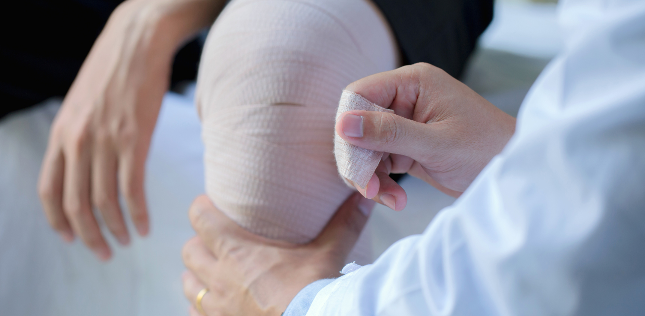 Medical professional wrapping a bandage around a patient’s injured knee during treatment or rehabilitation
