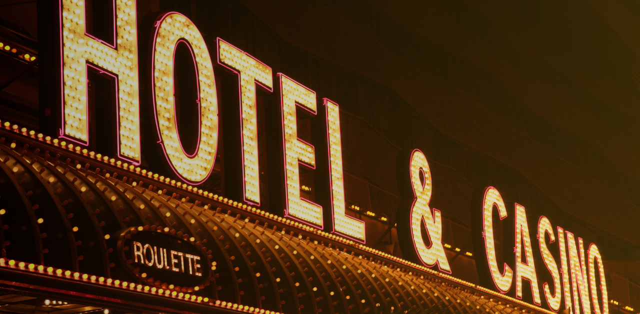 Brightly illuminated hotel and casino sign at night with neon lighting and a roulette sign below