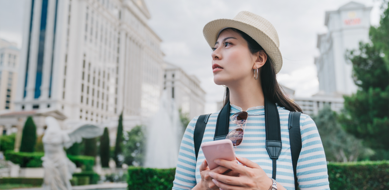 Tourist with a smartphone stands in a resort district, looking toward nearby hotel buildings