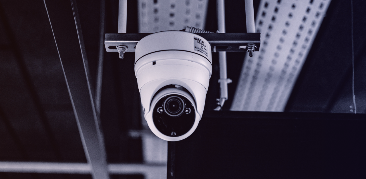 Close-up of a dome surveillance camera attached to an indoor ceiling