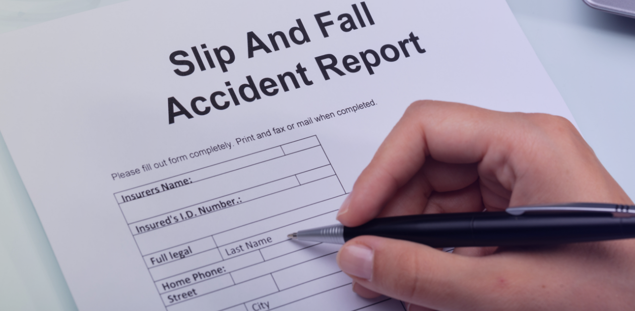 Close-up of a hand filling out a slip and fall accident report form with a pen
