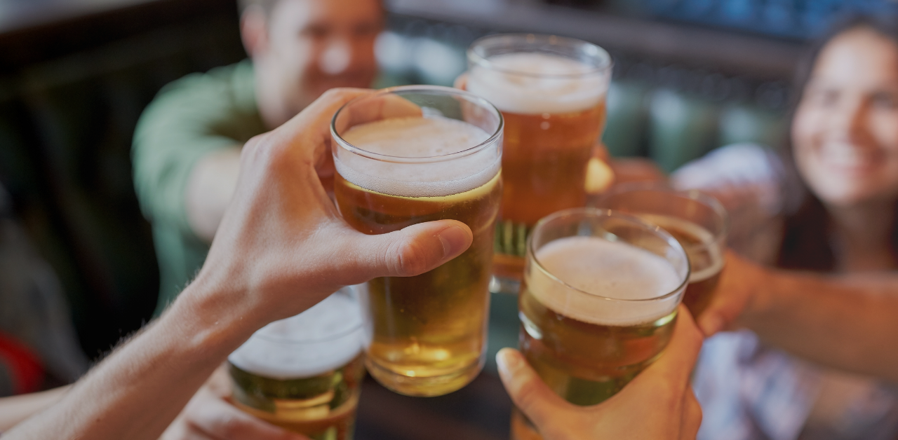 Friends raise glasses of beer in a toast at a bar or restaurant