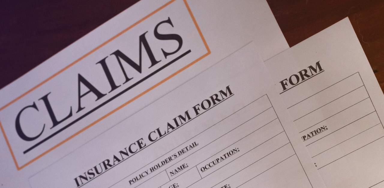 Insurance claim forms arranged on a desk, including a primary claims document