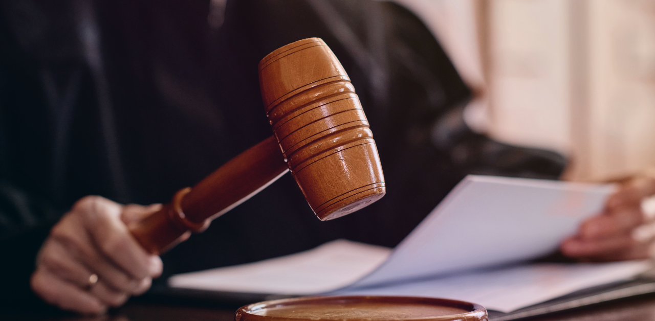Judge holds a gavel while reviewing documents at the bench