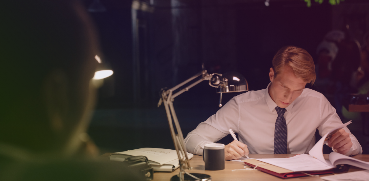Lawyer reviews and writes notes on legal documents while working late at a desk