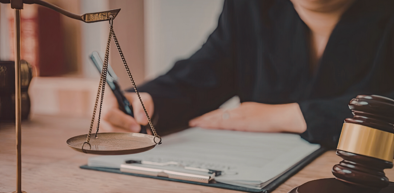 Lawyer reviews documents at a desk with scales of justice and a gavel nearby
