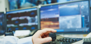 Security operator uses a joystick to monitor surveillance cameras on multiple screens
