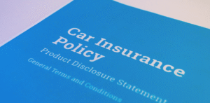 A close-up of a blue “Car Insurance Policy” document showing text about product disclosure statements and general terms and conditions