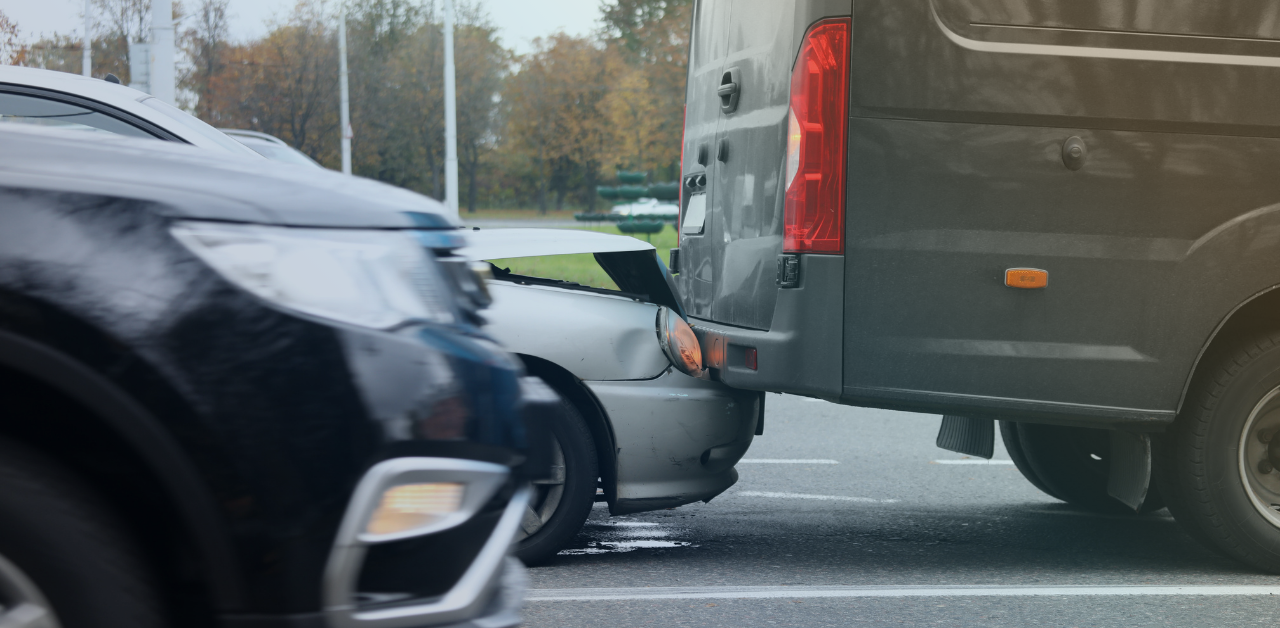 Car with front-end damage after a rear-end collision with a large van in traffic