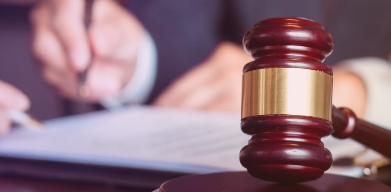 Close-up of a judge's gavel in front of a person signing a legal document