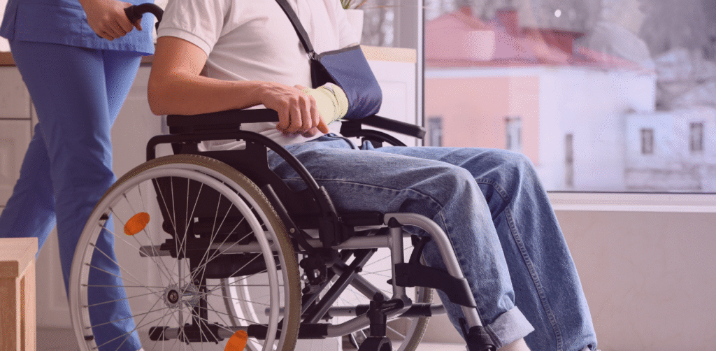 Healthcare worker assists a wheelchair user wearing an arm sling and wrist bandage