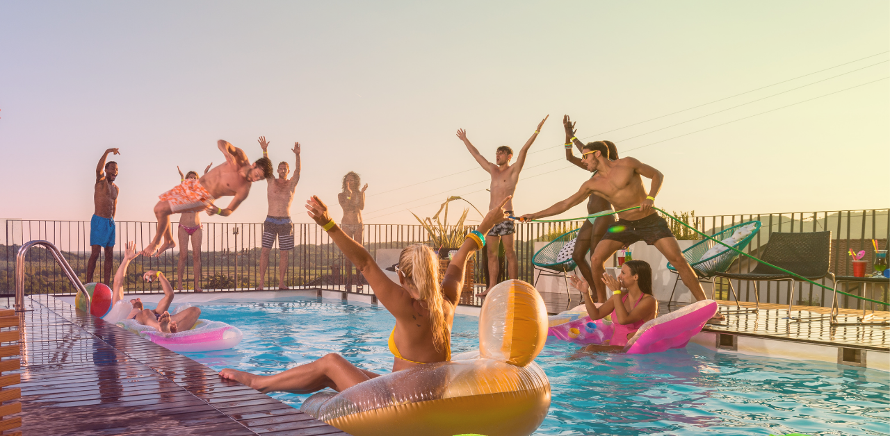People gather around a swimming pool, with several using inflatable floats and playing with a beach ball