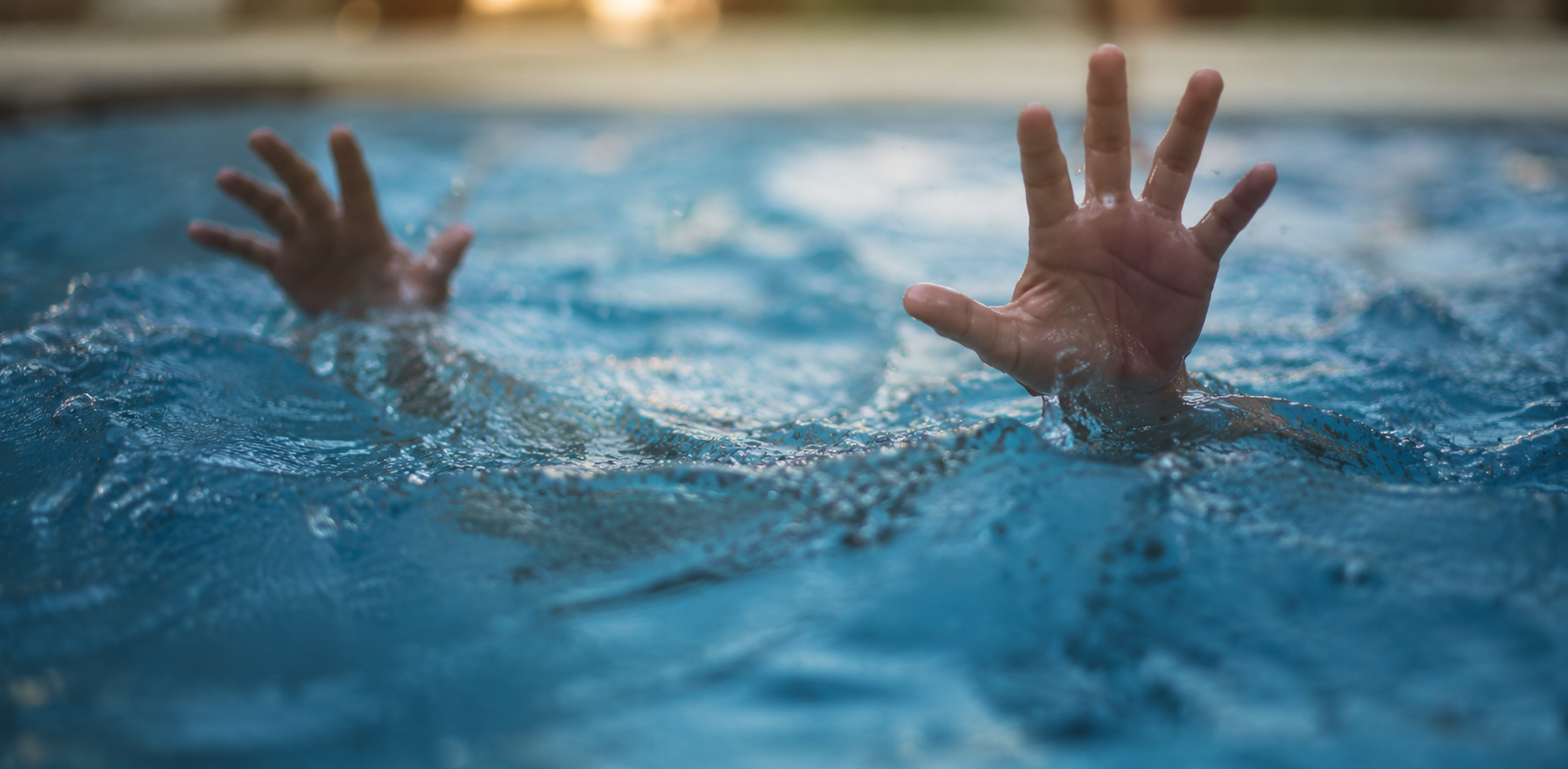 Two hands reach above churning pool water as a person appears to struggle to stay afloat